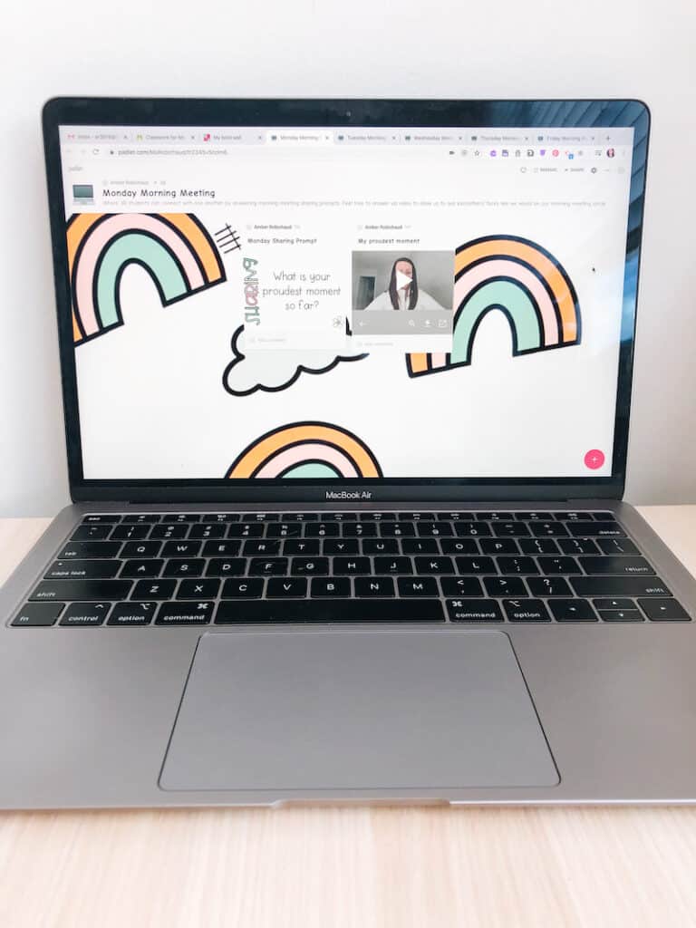 Open laptop showing online morning meeting padlet with rainbow background. Has a morning meeting sharing prompt and video post.