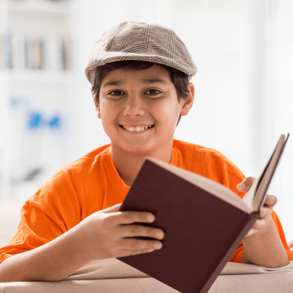 Child smiling as he reads a book during the classroom morning routine