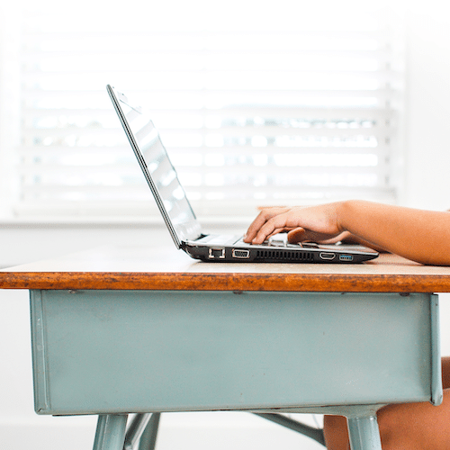 Child's hands with laptop on desk