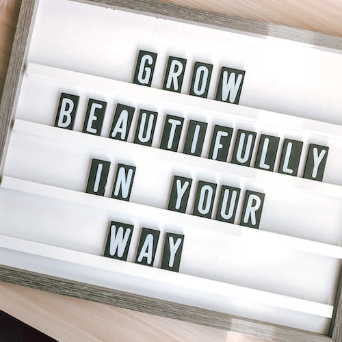 Wooden lettered sign with quote "grow beautifully in your way"