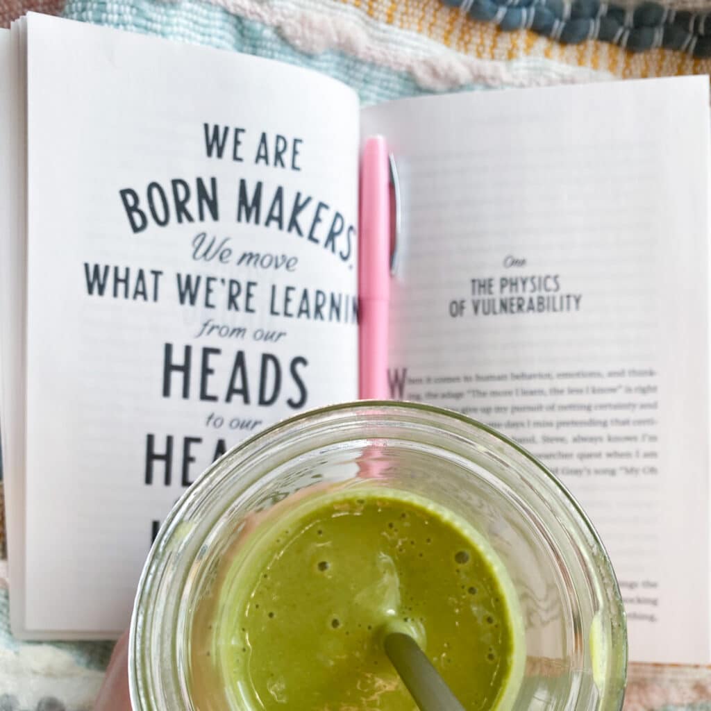 Green smoothie and open "Rising Strong" book with a pink flair pen
