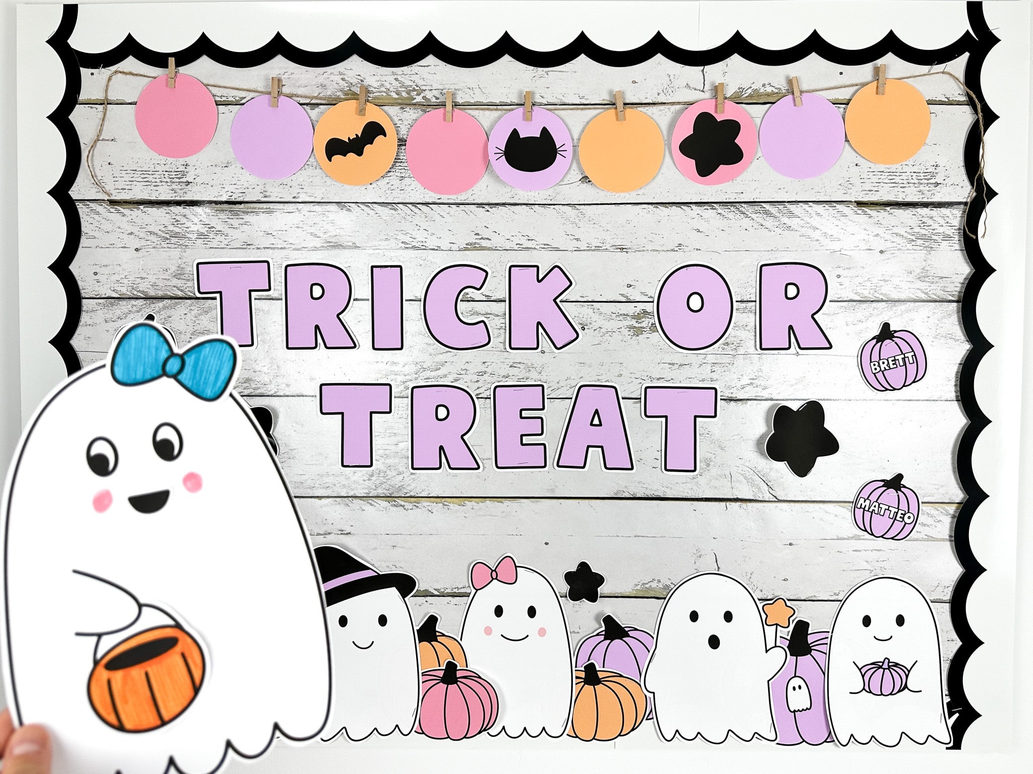 Ghost bulletin board with message that reads "trick or treat" featuring a ghost craft in front with a blue bow and trick or treat bucket- showing one of two Halloween bulletin board ideas